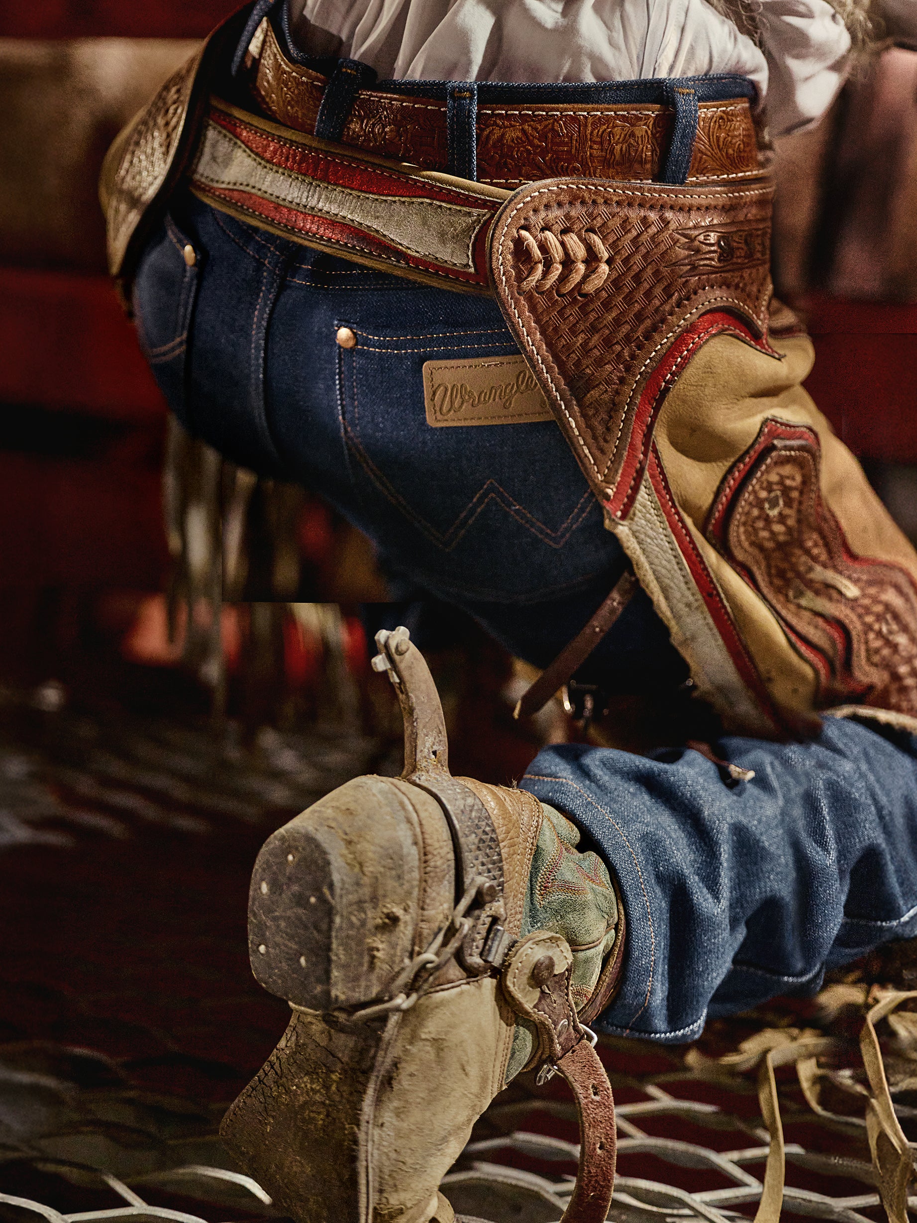 Close-up of a cowboy boot with a spurs and a detailed belt with a brand logo.